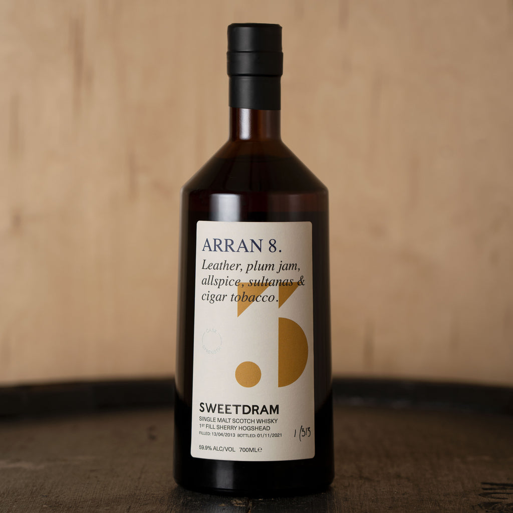 Close up of Arran 8 brown 700ml whisky bottle on top of dark wood cask.